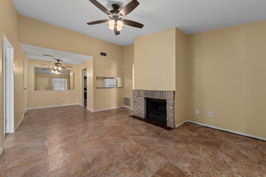 an empty room with a fireplace and a chandelier fan