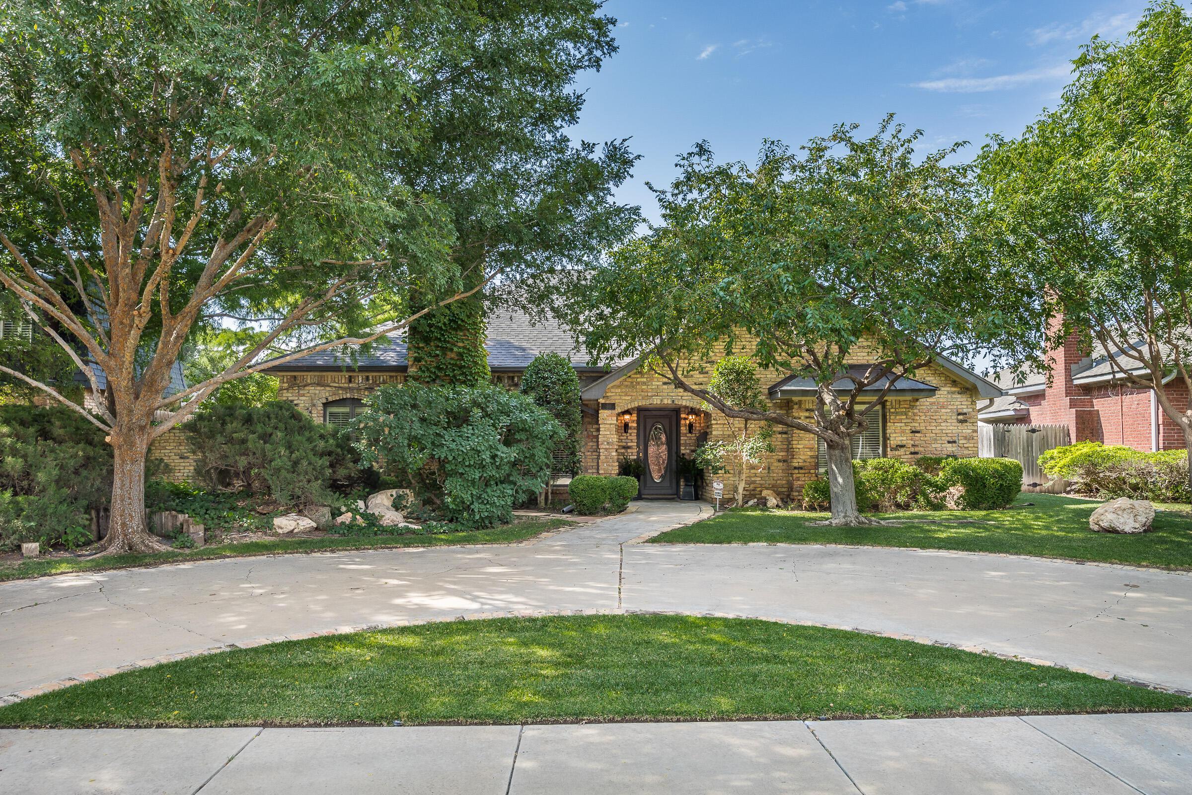 a front view of a house with a yard and trees