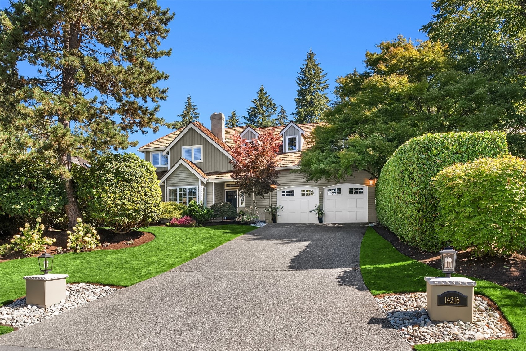 a view of a white house next to a yard with big trees