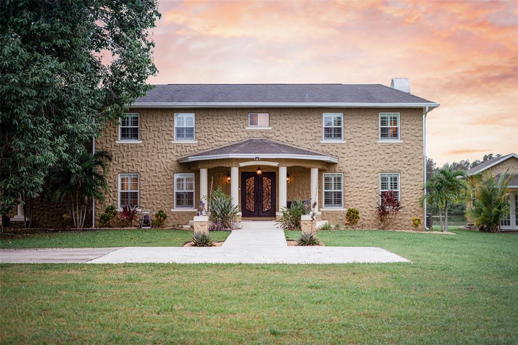 a front view of a house with a yard and trees