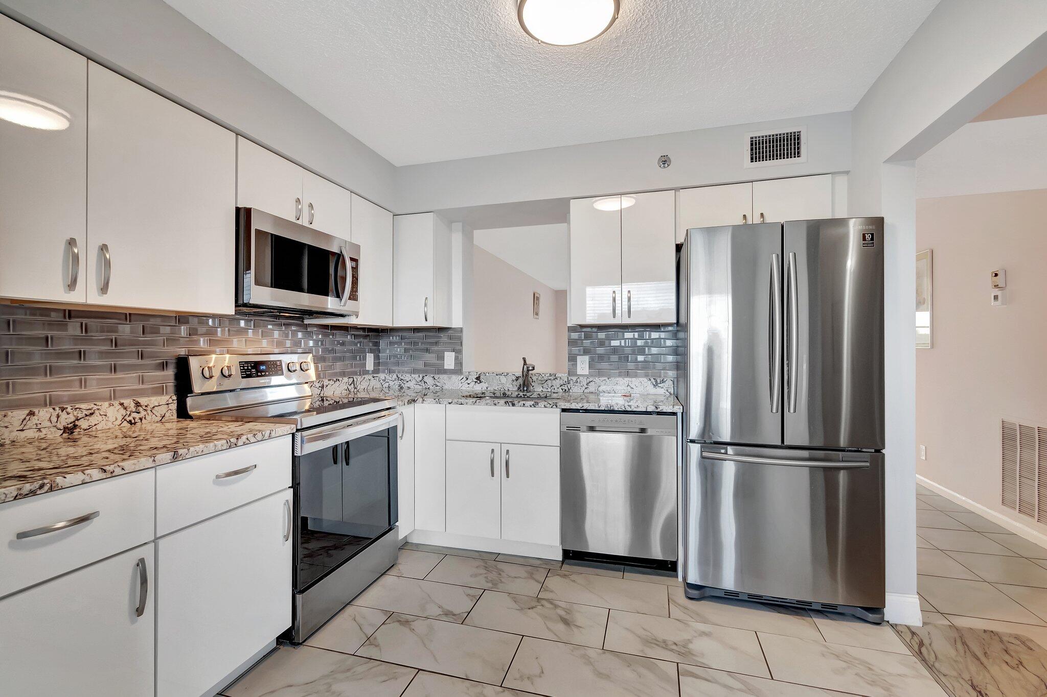 a kitchen with stainless steel appliances granite countertop a refrigerator sink and stove