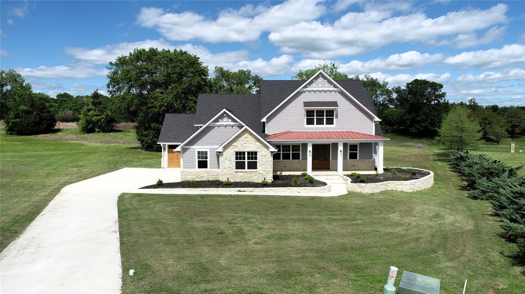 a front view of a house with a garden and trees