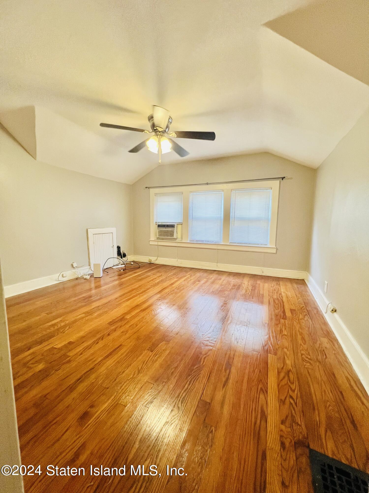 a view of empty room with wooden floor and fan