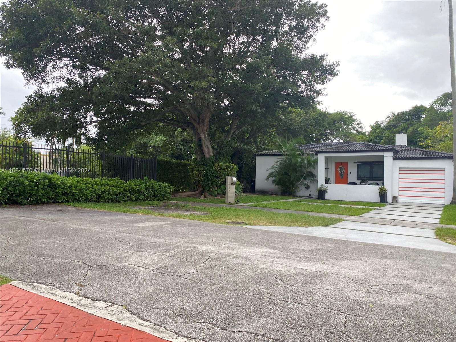 a view of a house with a yard and large trees