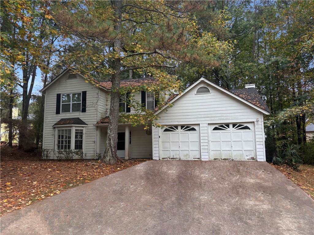 a view of a house with a yard and large tree