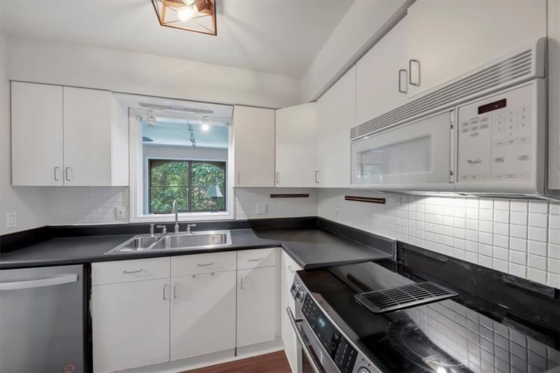 a kitchen with granite countertop a sink stove and cabinets