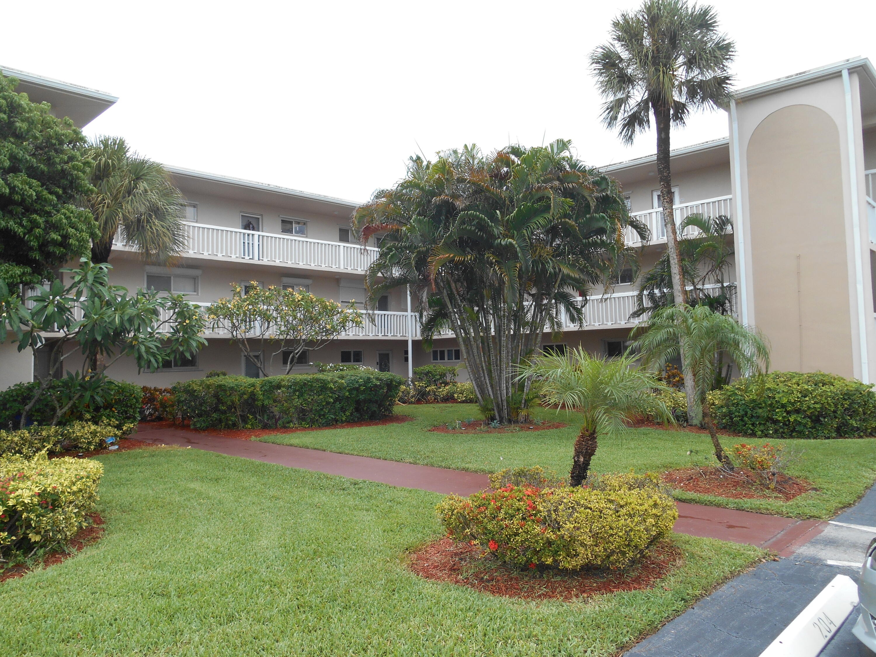 a front view of a house with a yard and palm trees