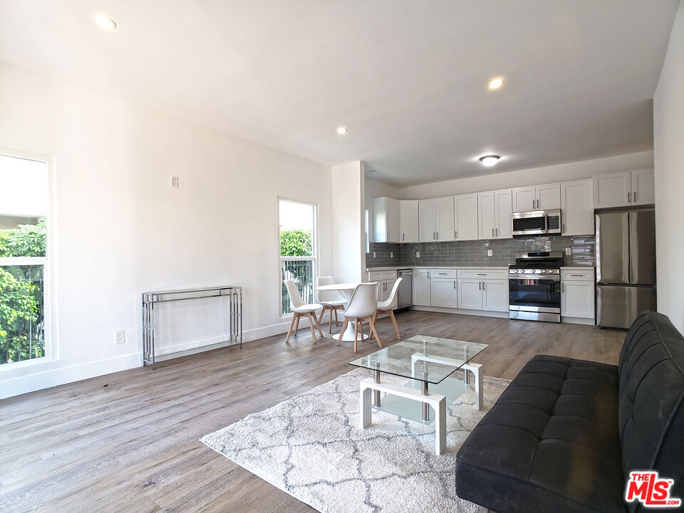 a living room with stainless steel appliances kitchen island granite countertop furniture and a wooden floor