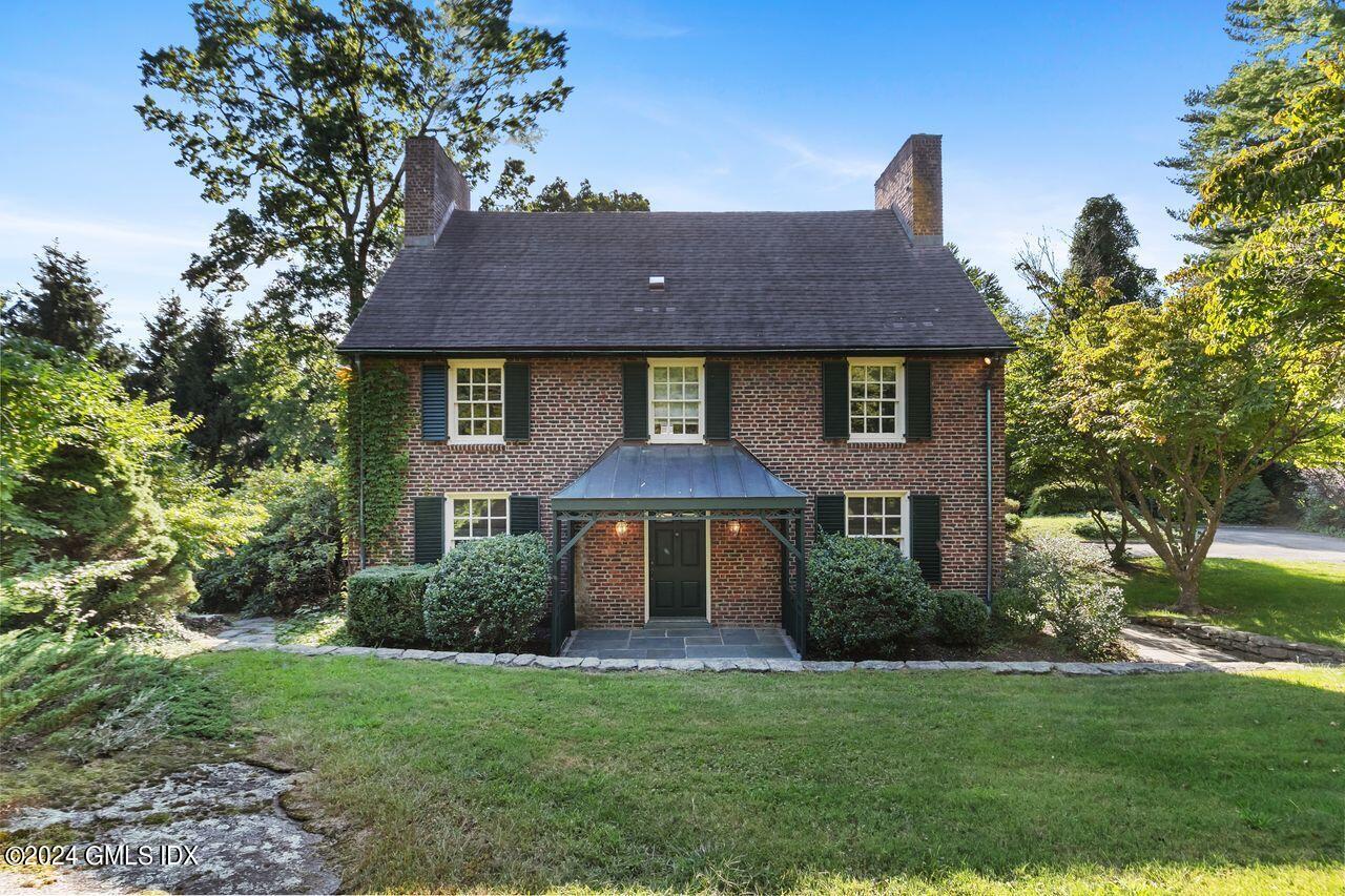 a front view of a house with yard and trees