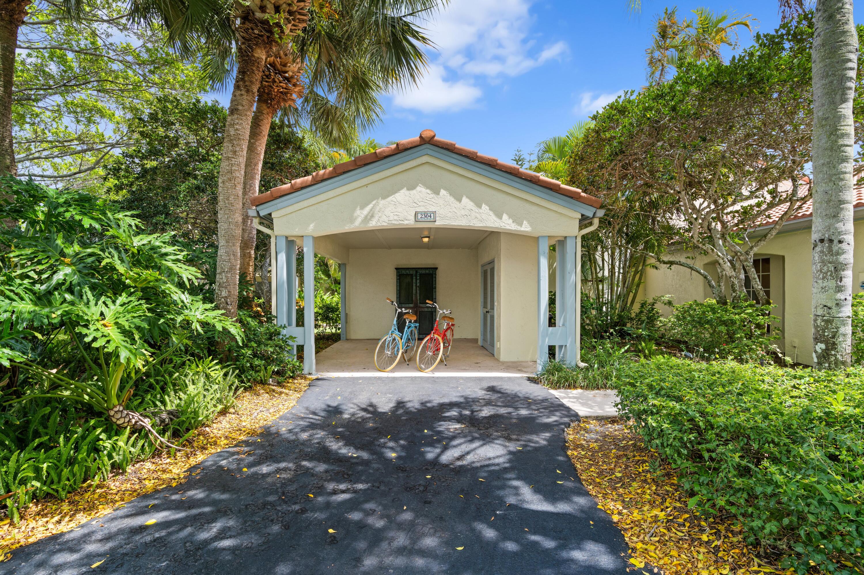 a view of a house with palm trees and a small yard