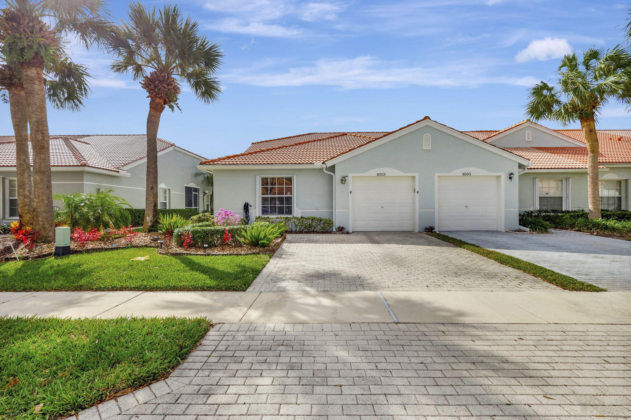 a view of a white house with a yard and palm trees