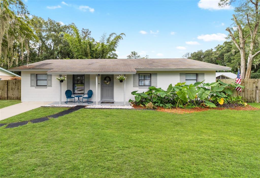 a backyard of a house with table and chairs plants and large tree