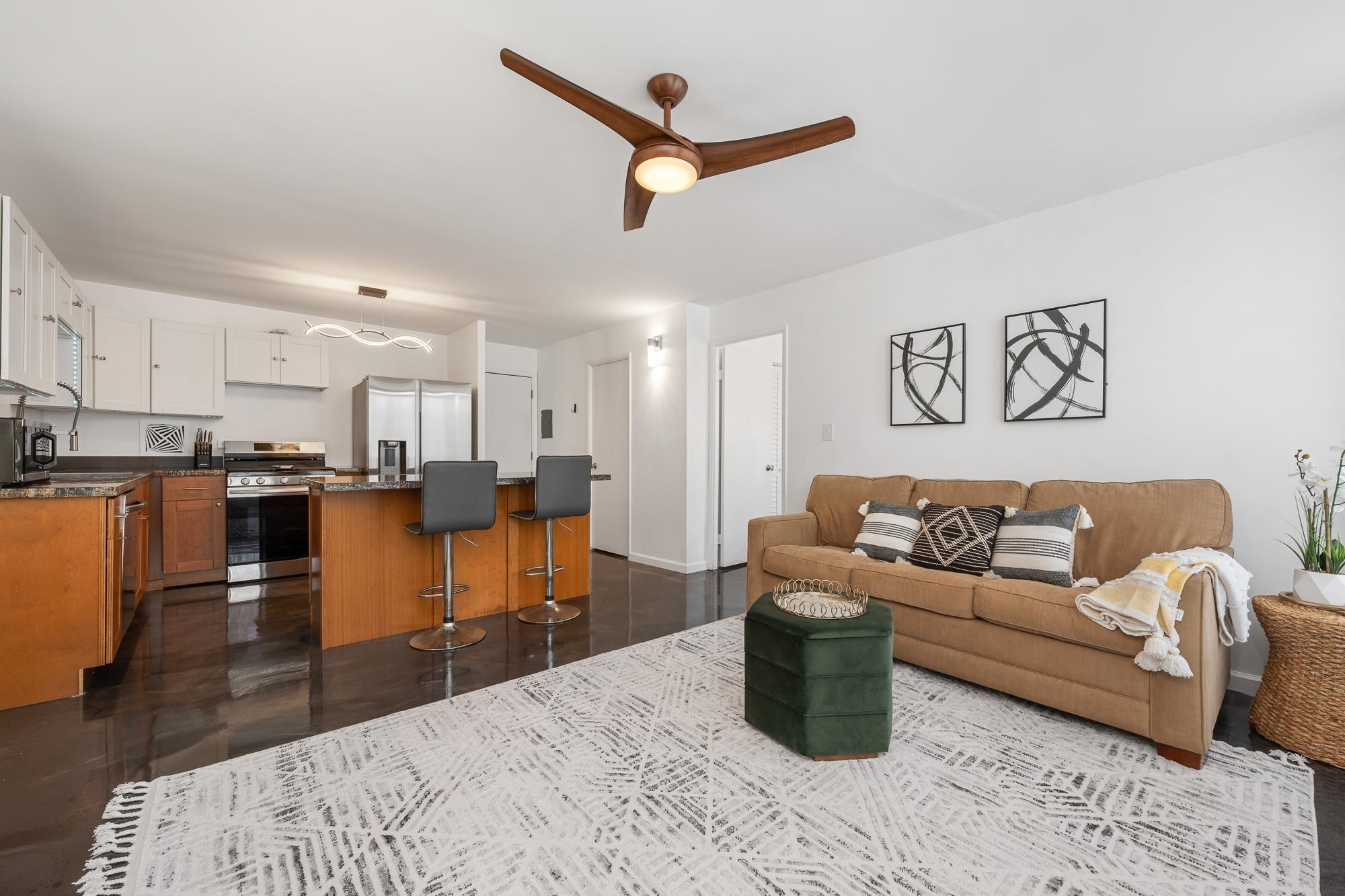 a living room with furniture kitchen view and a wooden floor