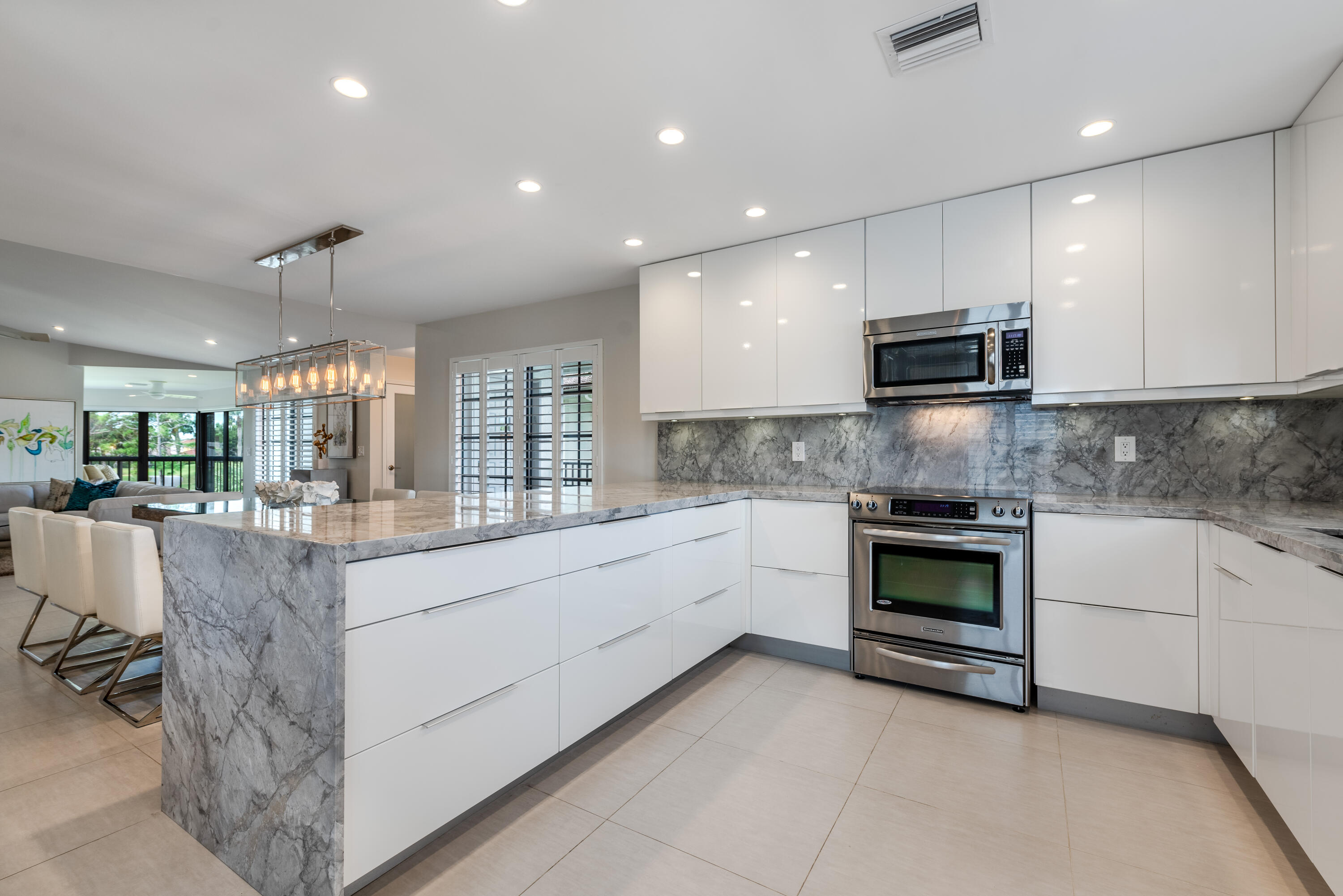 a large white kitchen with stainless steel appliances granite countertop a stove and a sink with granite countertops