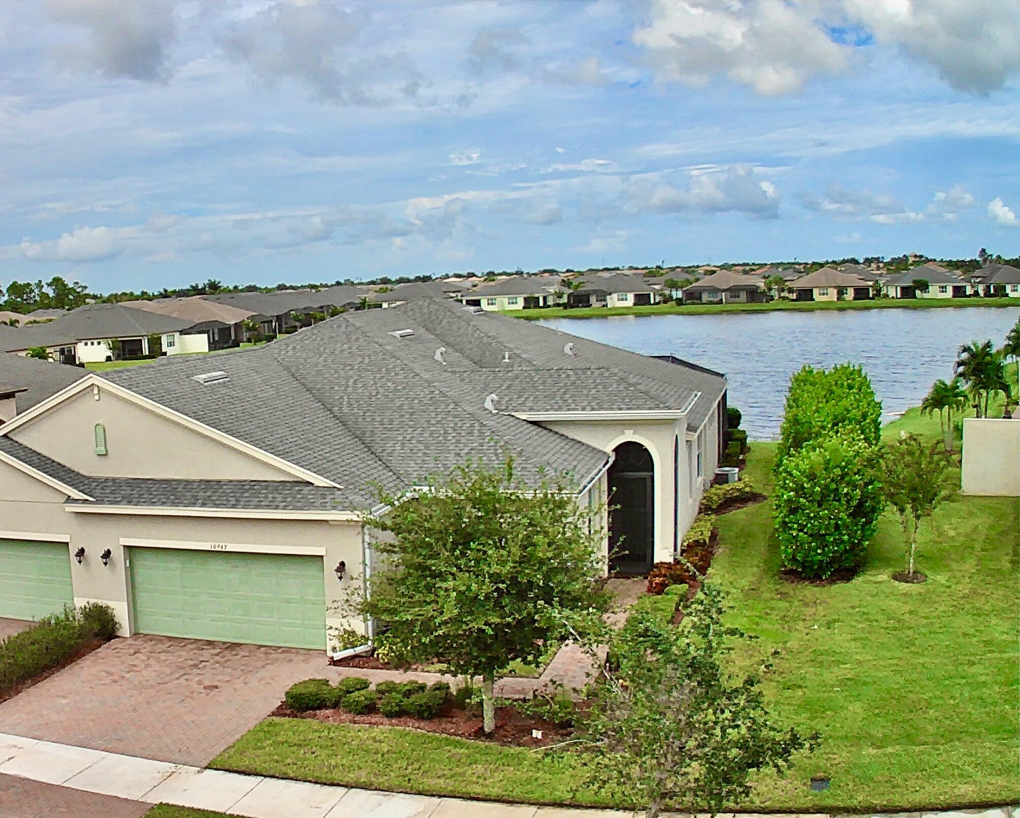 an aerial view of a house with green landscape and water view