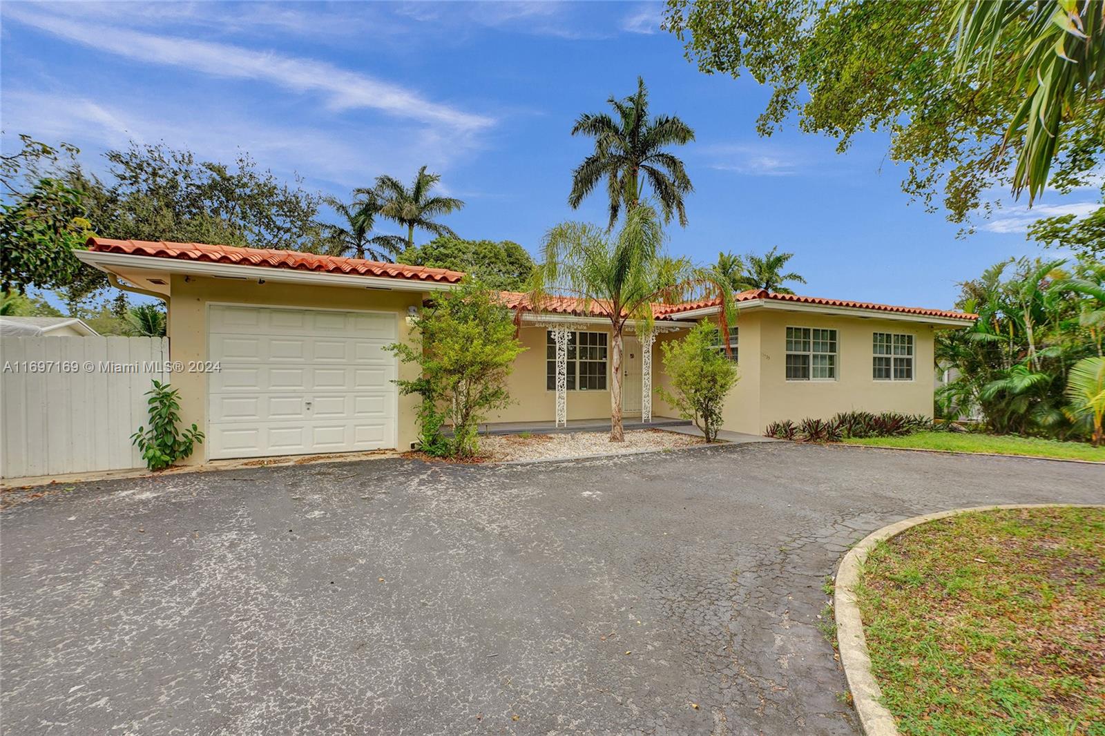 front view of a house with a yard and palm trees