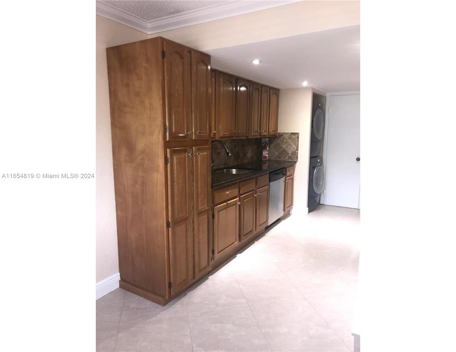 a view of a hallway with stainless steel appliances granite countertop cabinets and wooden floor