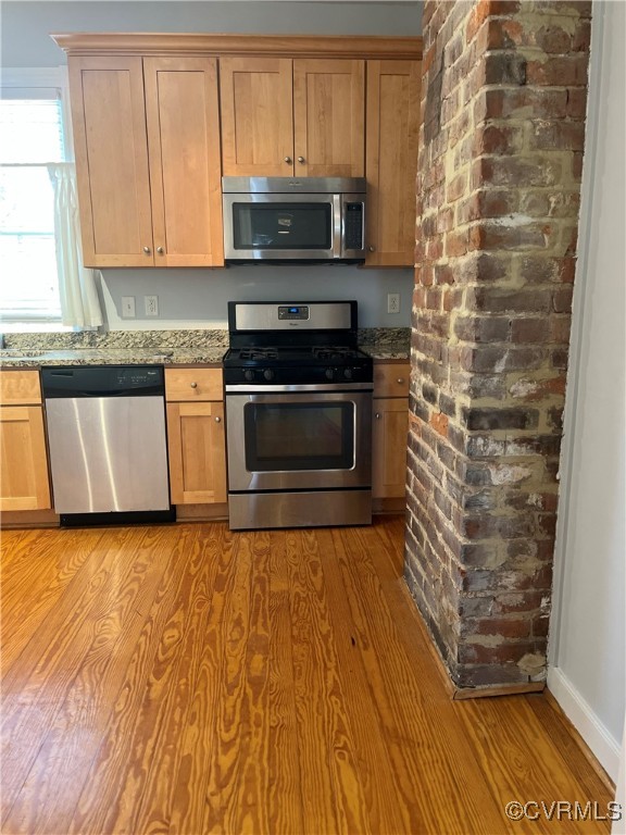 Kitchen featuring granite countertops, light wood