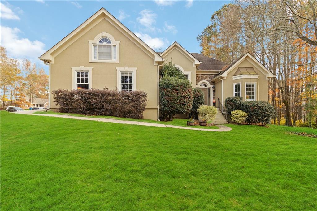 a front view of a house with a yard and green space