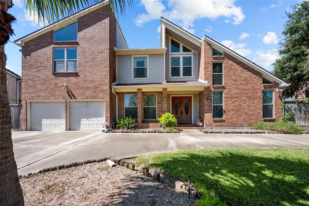 This is a two-story brick home with a two-car garage, a well-maintained front yard, and an ornate front door, featuring a mix of traditional and modern architectural elements.