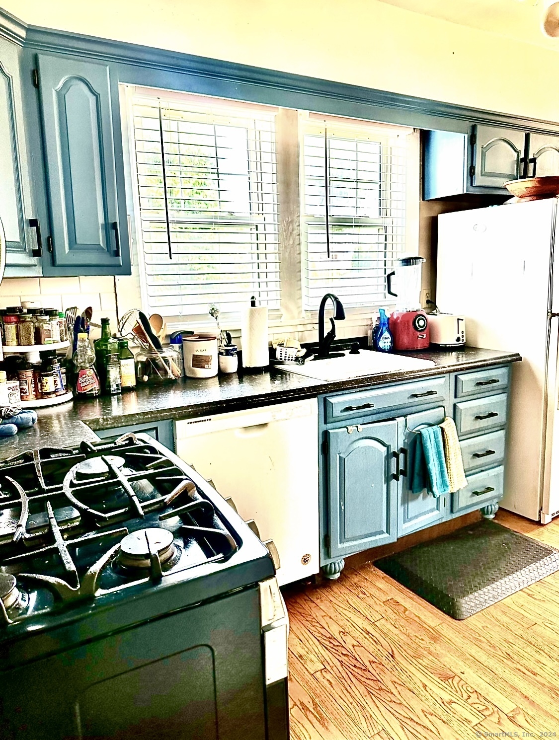 a kitchen with a stove a sink and a wooden floor