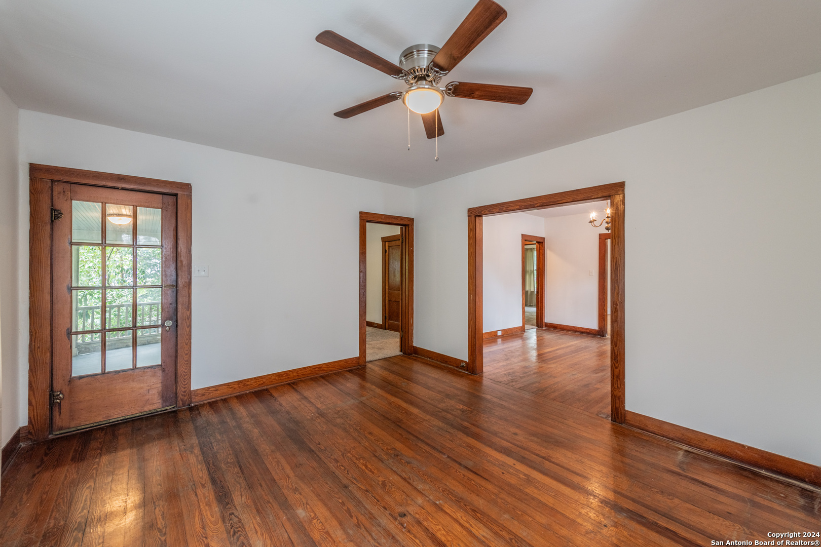 a view of an empty room with window and wooden floor