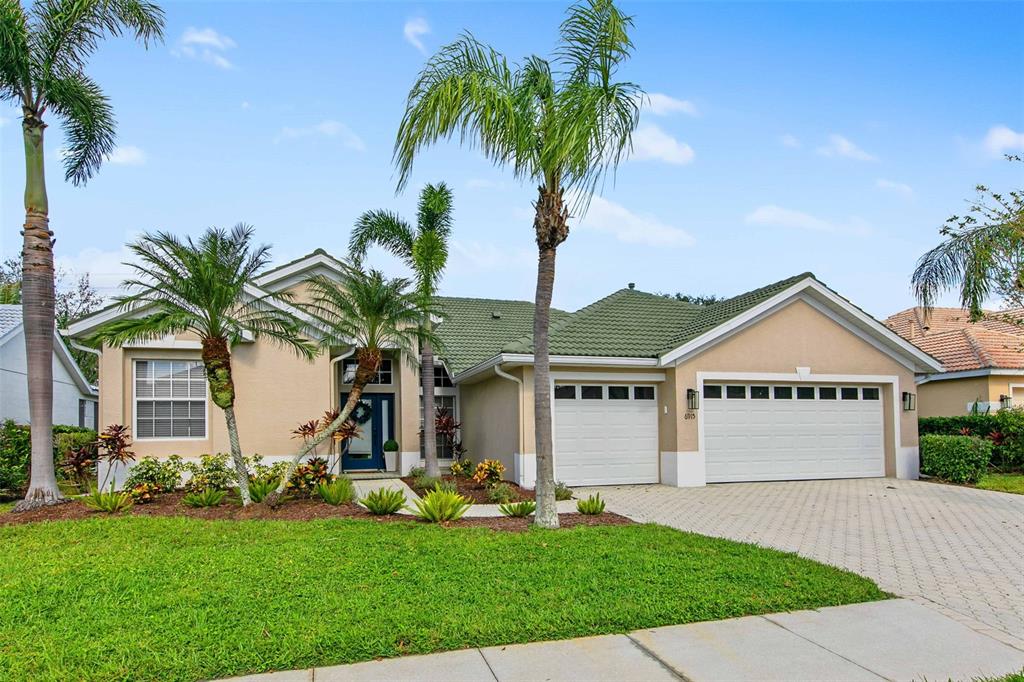 a front view of a house with a garden and palm trees