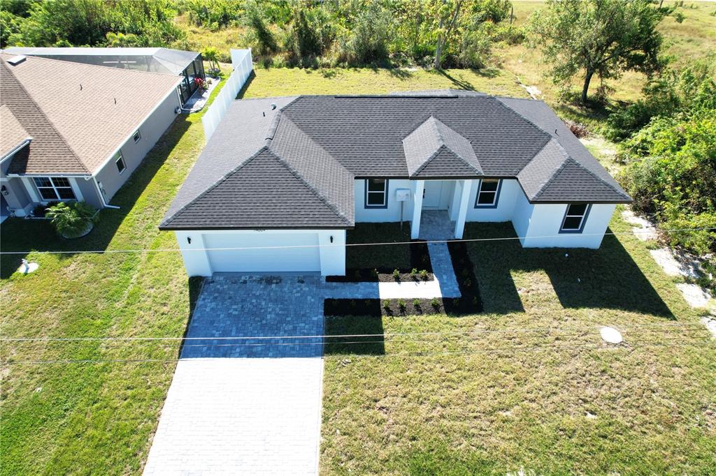 an aerial view of a house with swimming pool and large trees