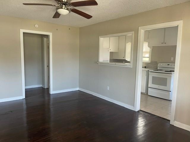 an empty room with wooden floor a ceiling fan and windows