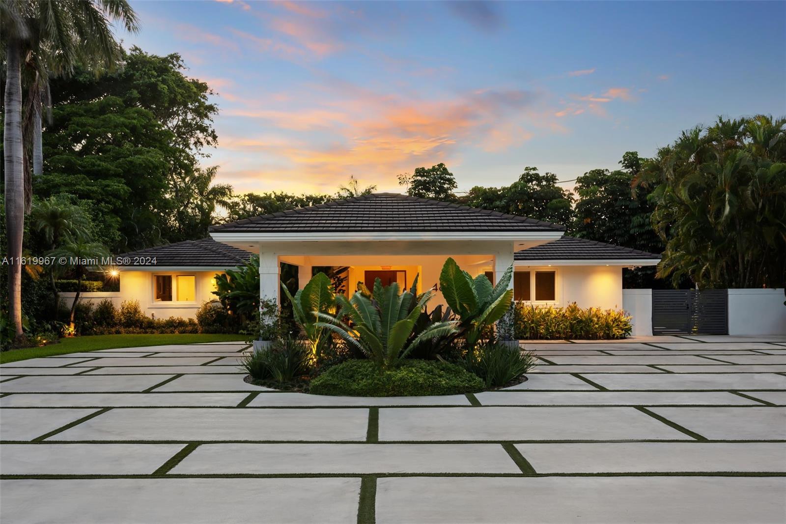 a front view of a house with a yard and potted plants