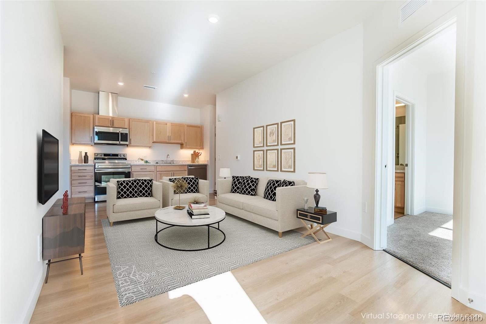 a living room with furniture white walls and kitchen view