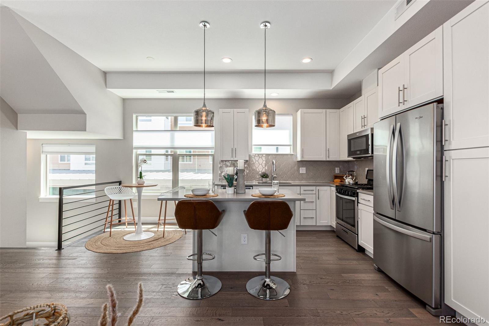 a kitchen with stainless steel appliances granite countertop a stove a refrigerator a kitchen island a dining table and chairs with wooden floor