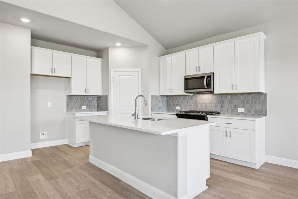 a kitchen with stainless steel appliances granite countertop a sink a stove a refrigerator and white cabinets