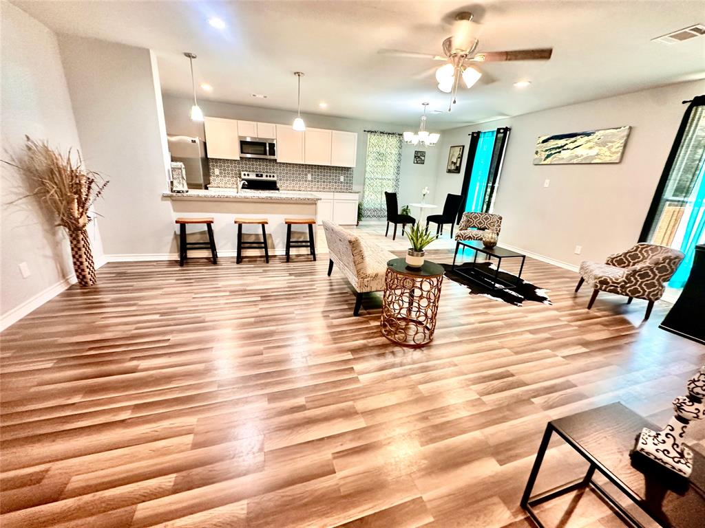 a view of a kitchen with kitchen island stainless steel appliances wooden floor and chair