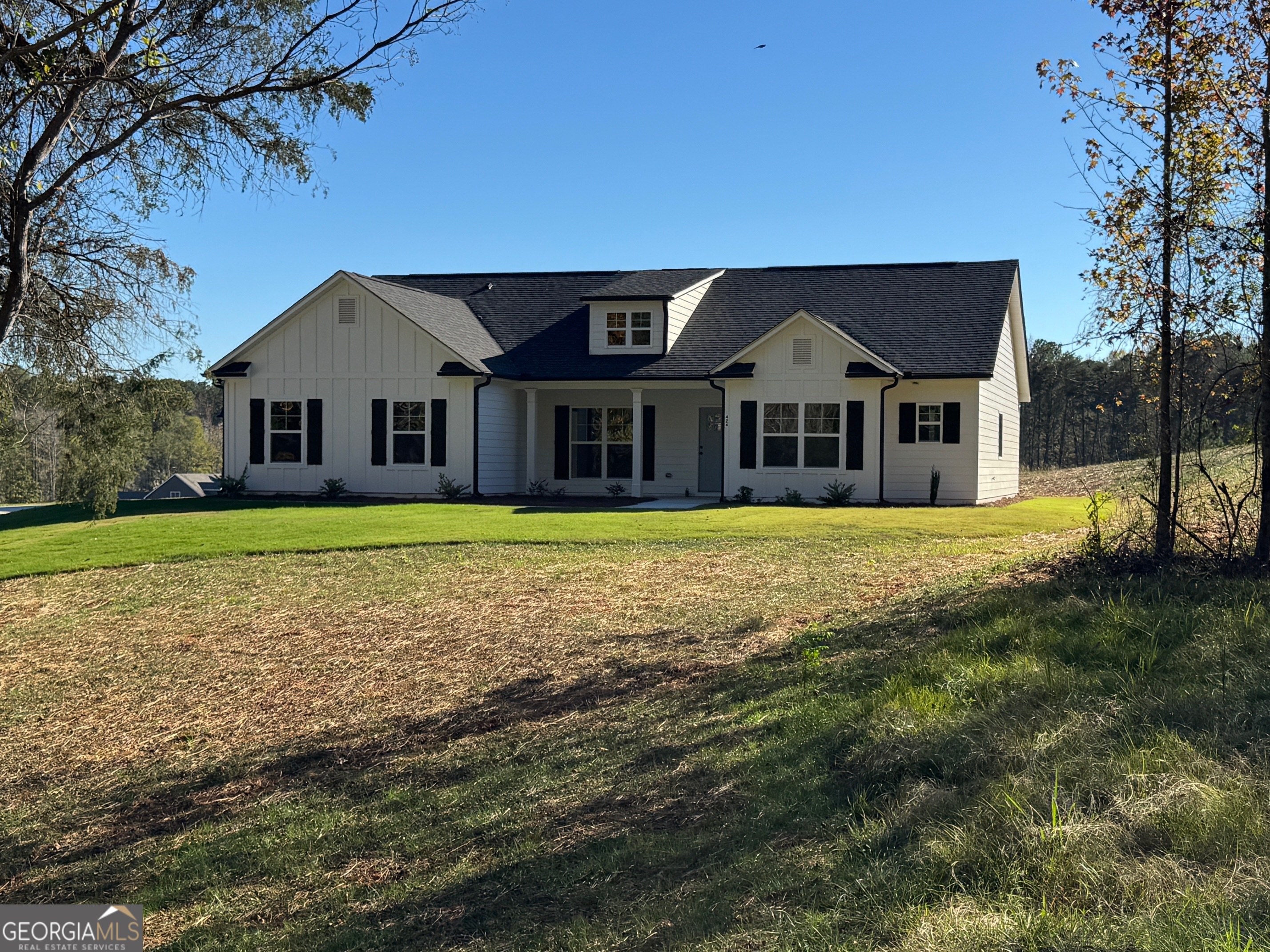 a front view of a house with a garden and trees