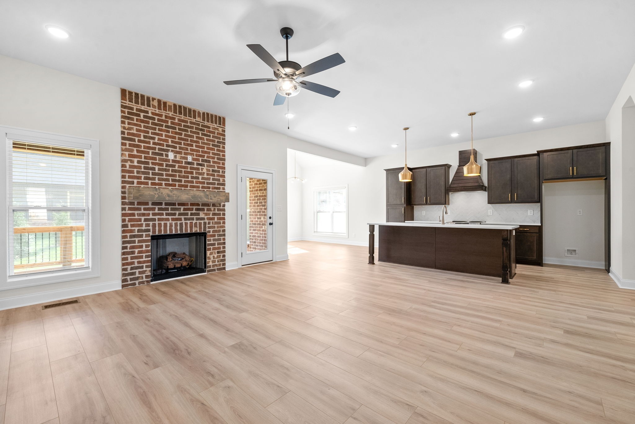 a view of an empty room with a kitchen and a fireplace