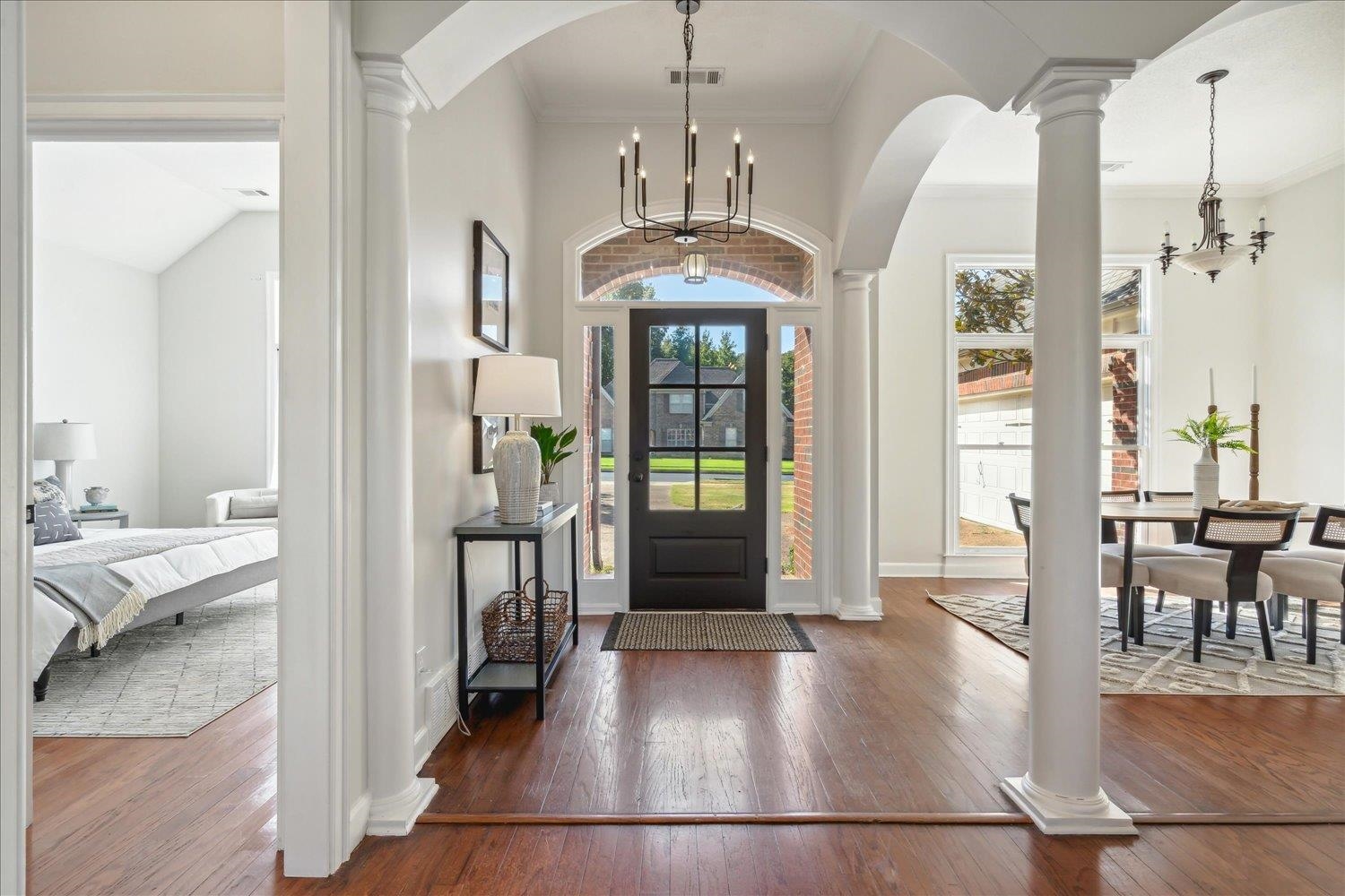 Entrance foyer featuring ornamental molding, ornate columns, an inviting chandelier, and dark hardwood / wood-style flooring