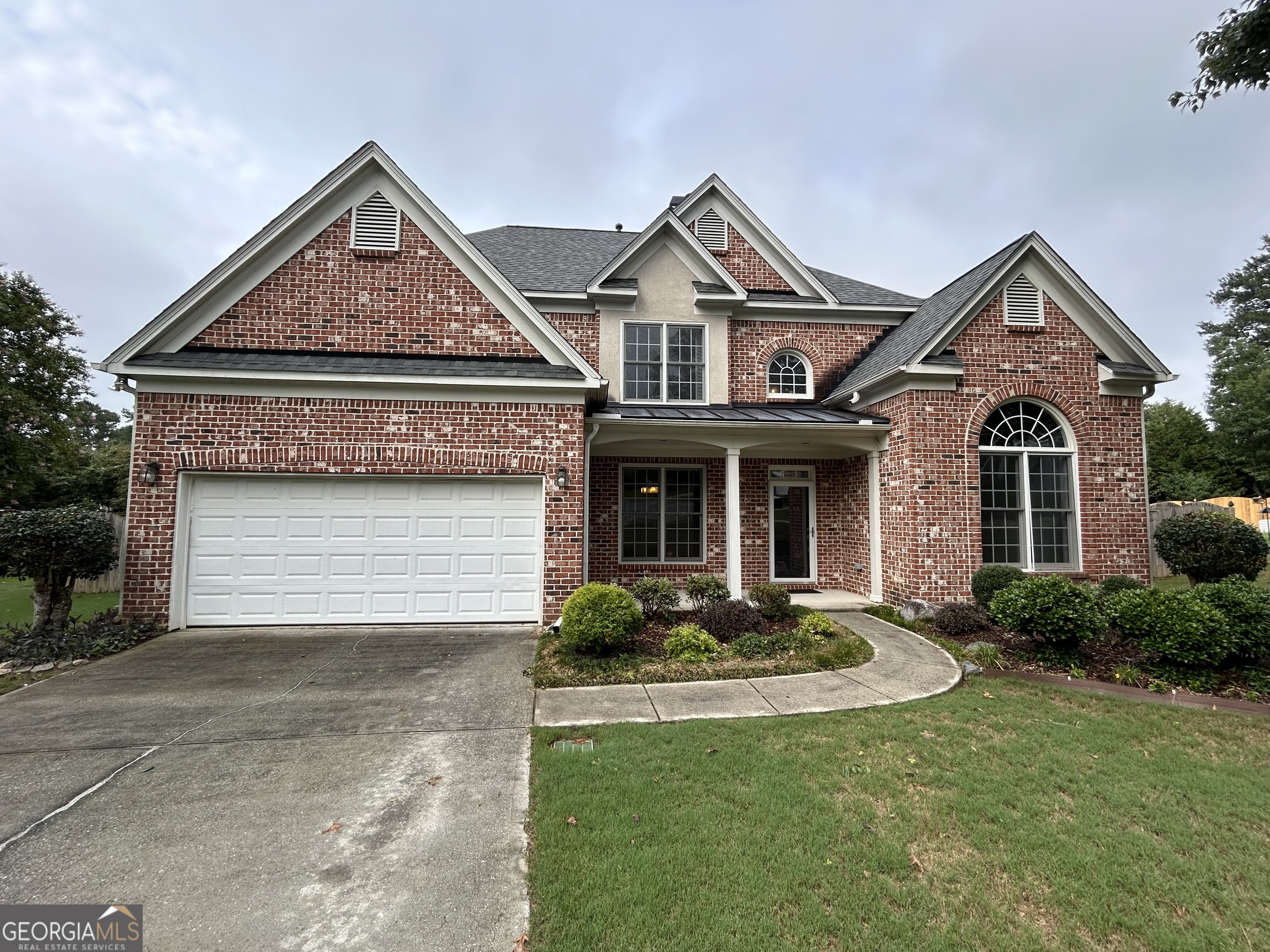 a front view of a house with yard and parking