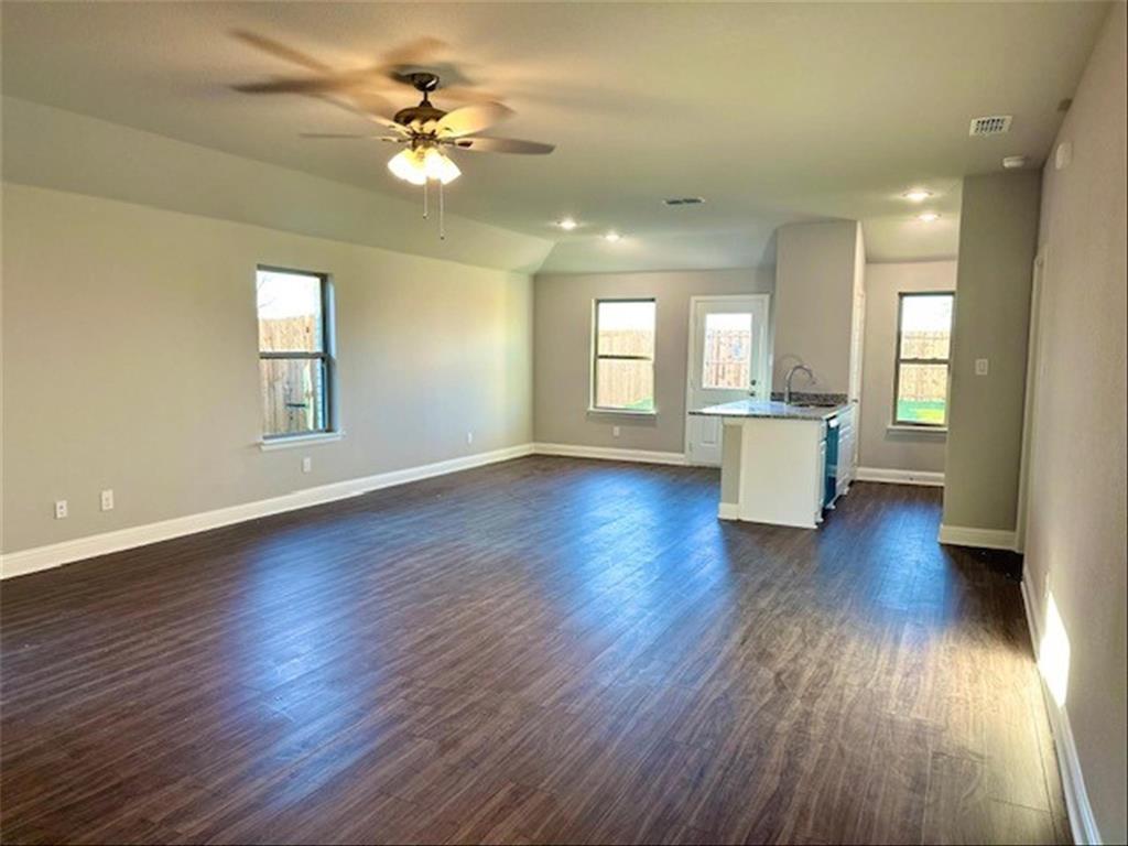 a view of an empty room with window and wooden floor