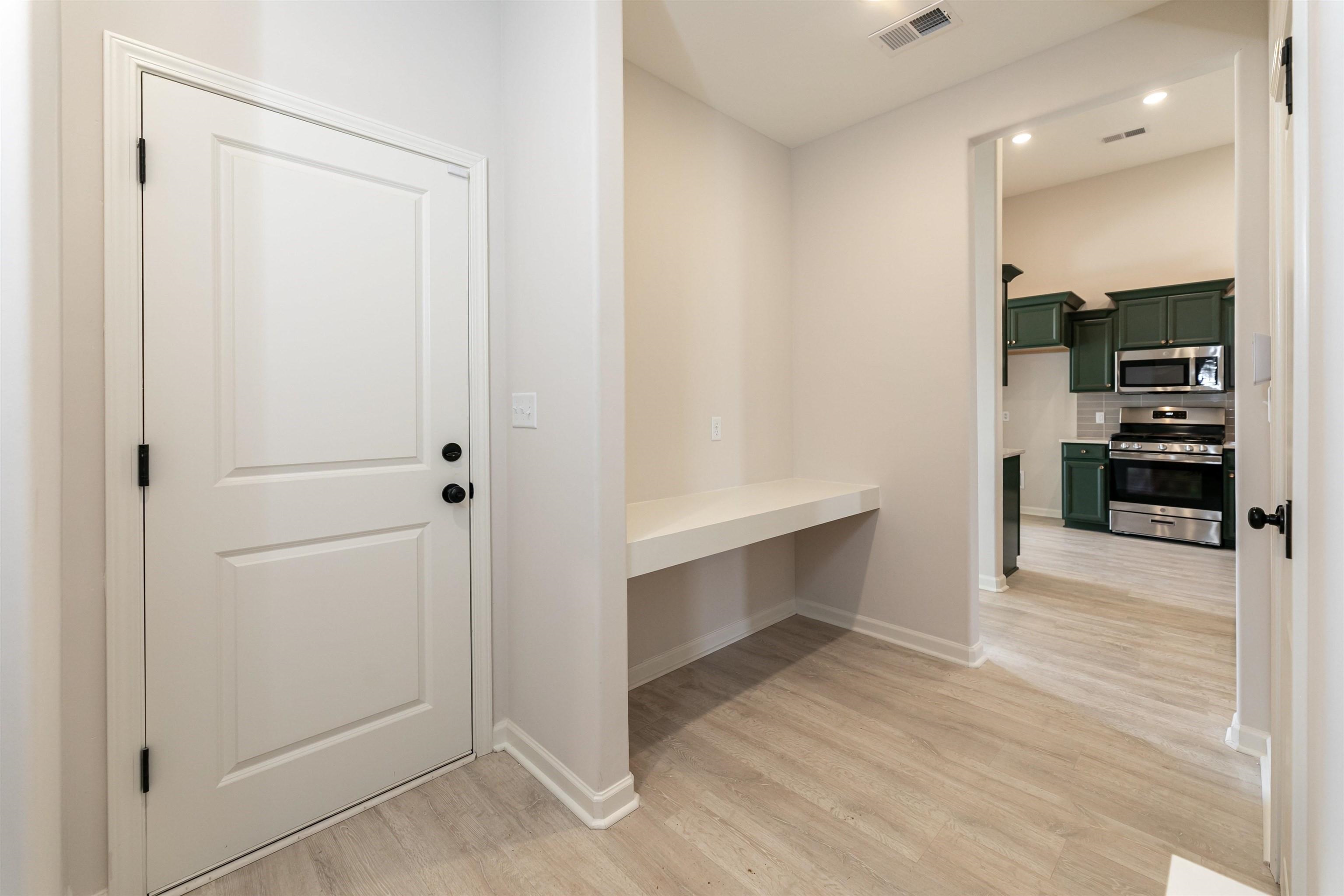 a view of an empty room and kitchen with sink wooden floor and windows