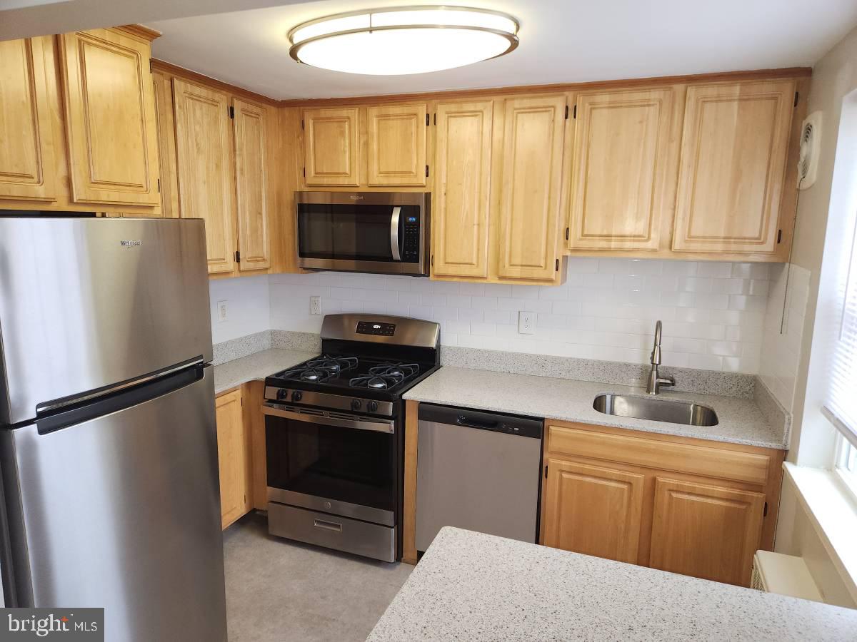 a kitchen with stainless steel appliances granite countertop a refrigerator sink and stove