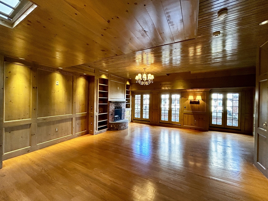 a view of an empty room with wooden floor and windows