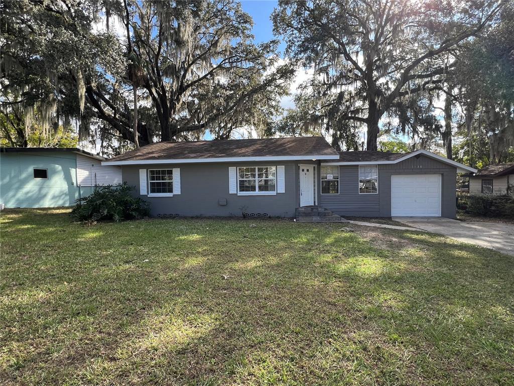 a view of a house with a yard and large tree