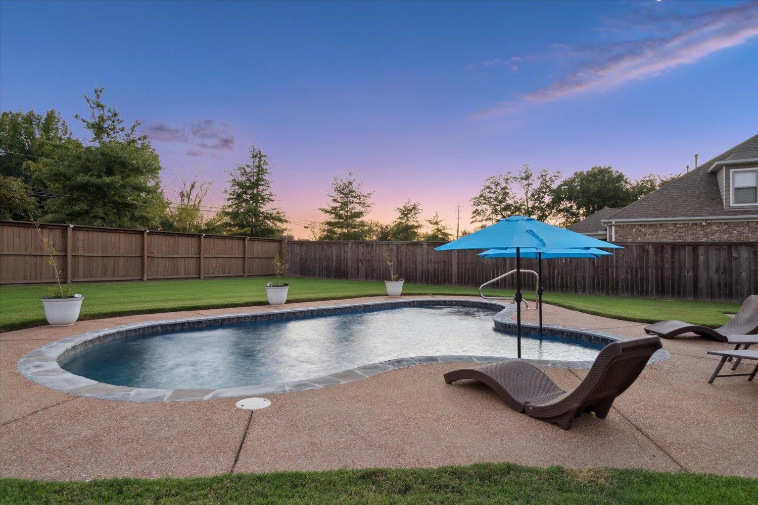 a swimming pool with outdoor seating and yard in the back