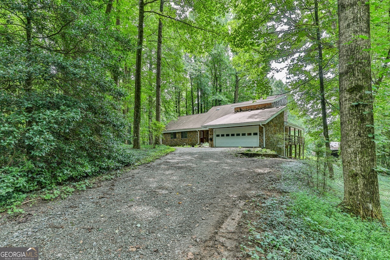 a view of a house with a yard and large trees