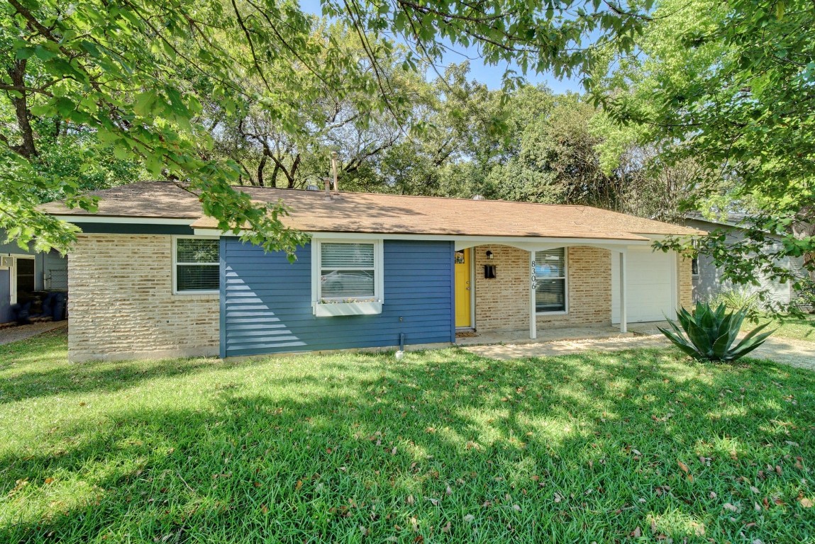 a view of a house with a yard and a large tree