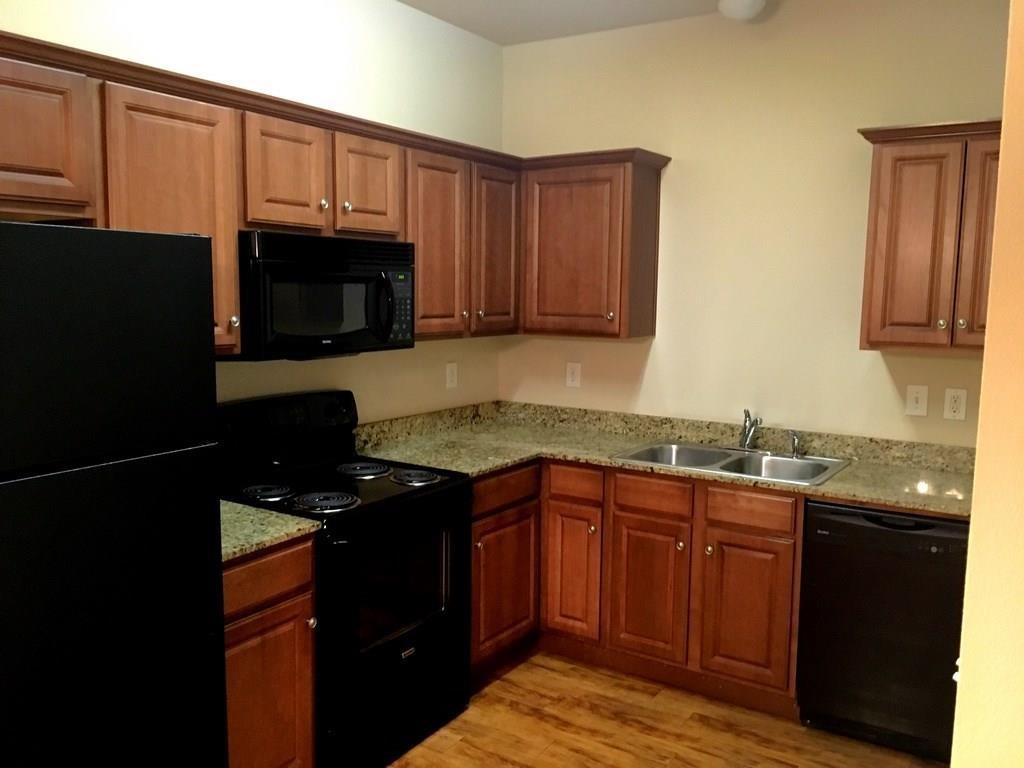 a kitchen with granite countertop wooden cabinets stainless steel appliances and a sink