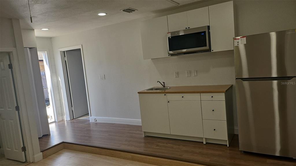 a view of a kitchen with a fridge and wooden floor