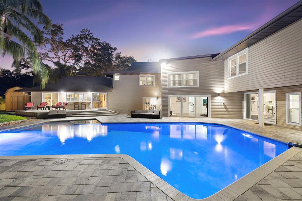 a large pool that has lawn chairs under an umbrella