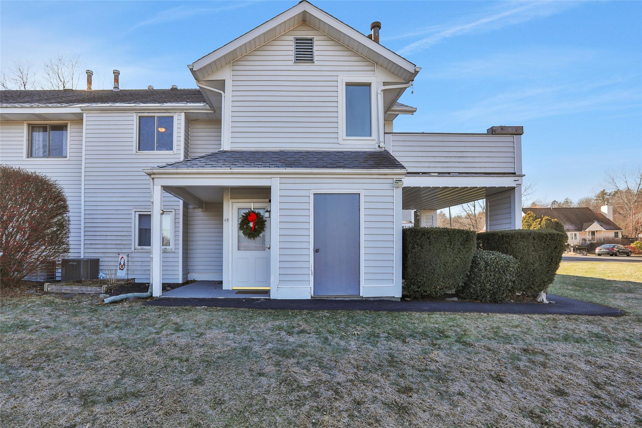 Back of house with a lawn, a balcony, and central AC unit